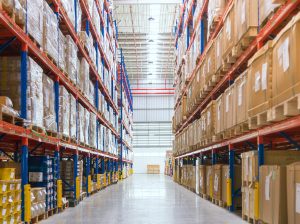 Rows of shelves with goods boxes in huge distribution warehouse at industrial storage factory