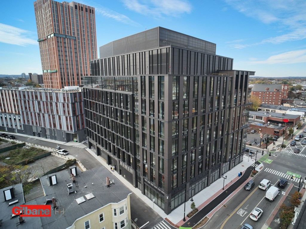 Mid-rise charcoal-gray office building with two setback levels at the top