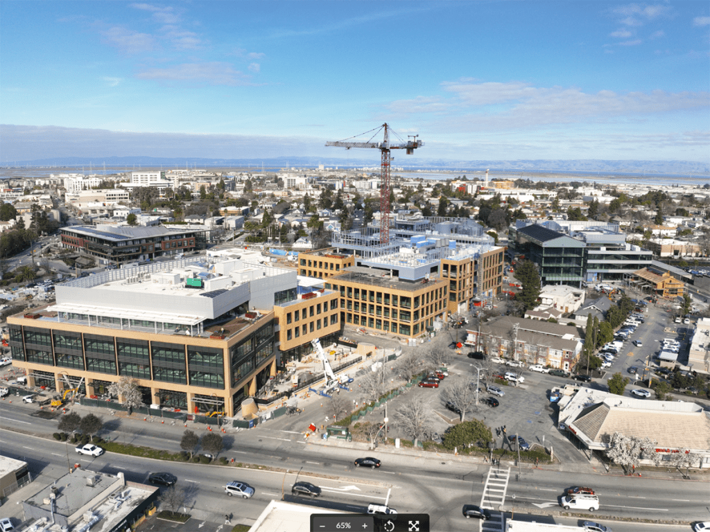 aerial view of a construction site with multiple low-rise buildings and a tower crane in the center