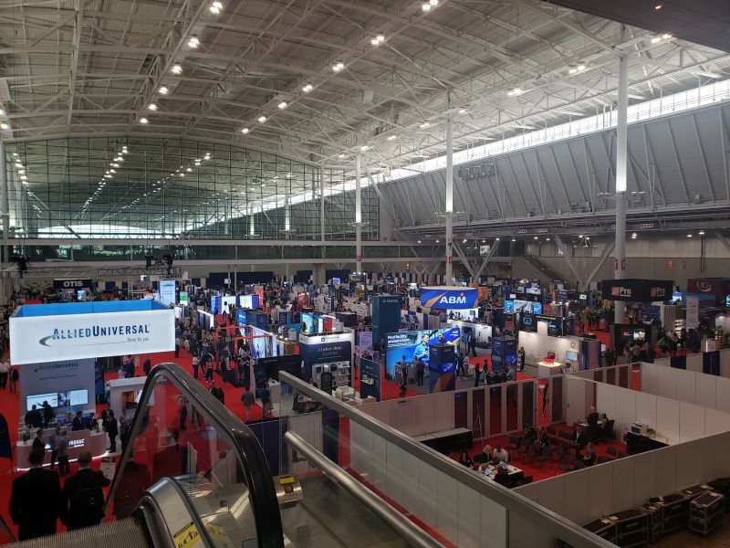 Elevated view of large convention center exhibit hall with booths and conference attendees
