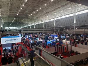 Elevated view of large convention center exhibit hall with booths and conference attendees