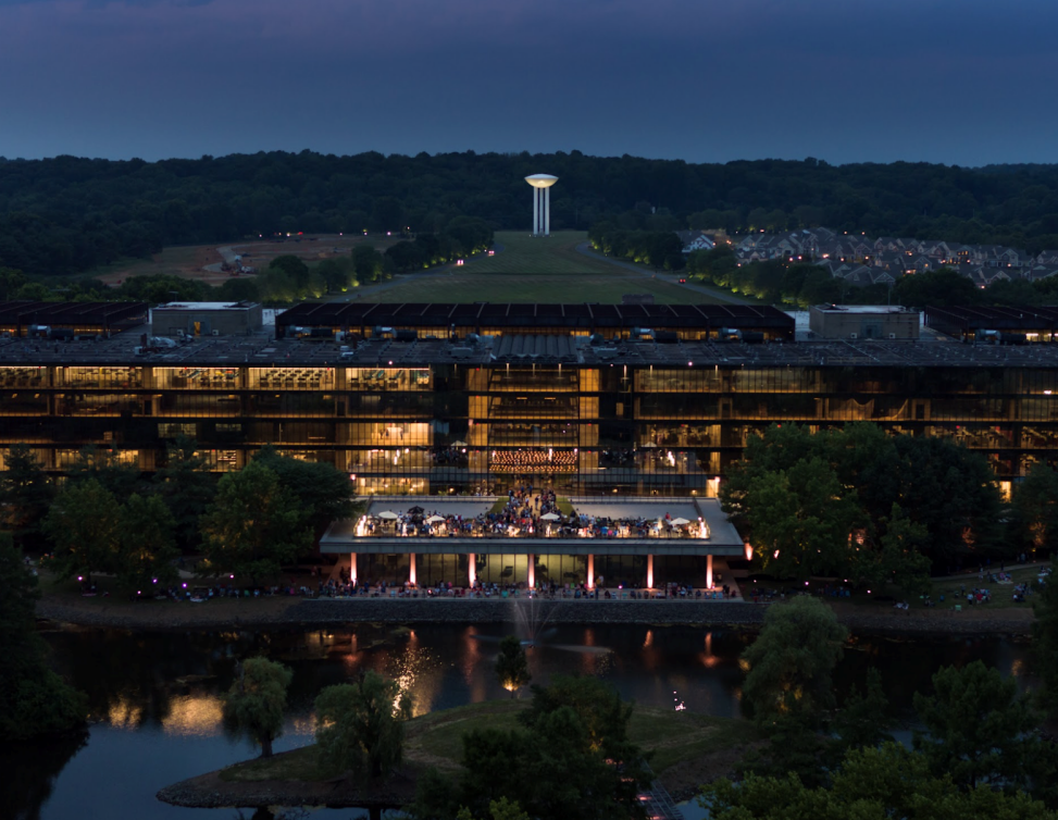 A wide shot of Bell Works showcasing its striking mid-century modern architecture—clean lines, expansive glass walls, and geometric forms. The building’s flexible, open layout is visible through the glass façade, emphasizing its adaptability for filming, large-scale productions, and the growing trend of pop culture placemaking. The overall atmosphere is sleek, timeless, and cinematic.