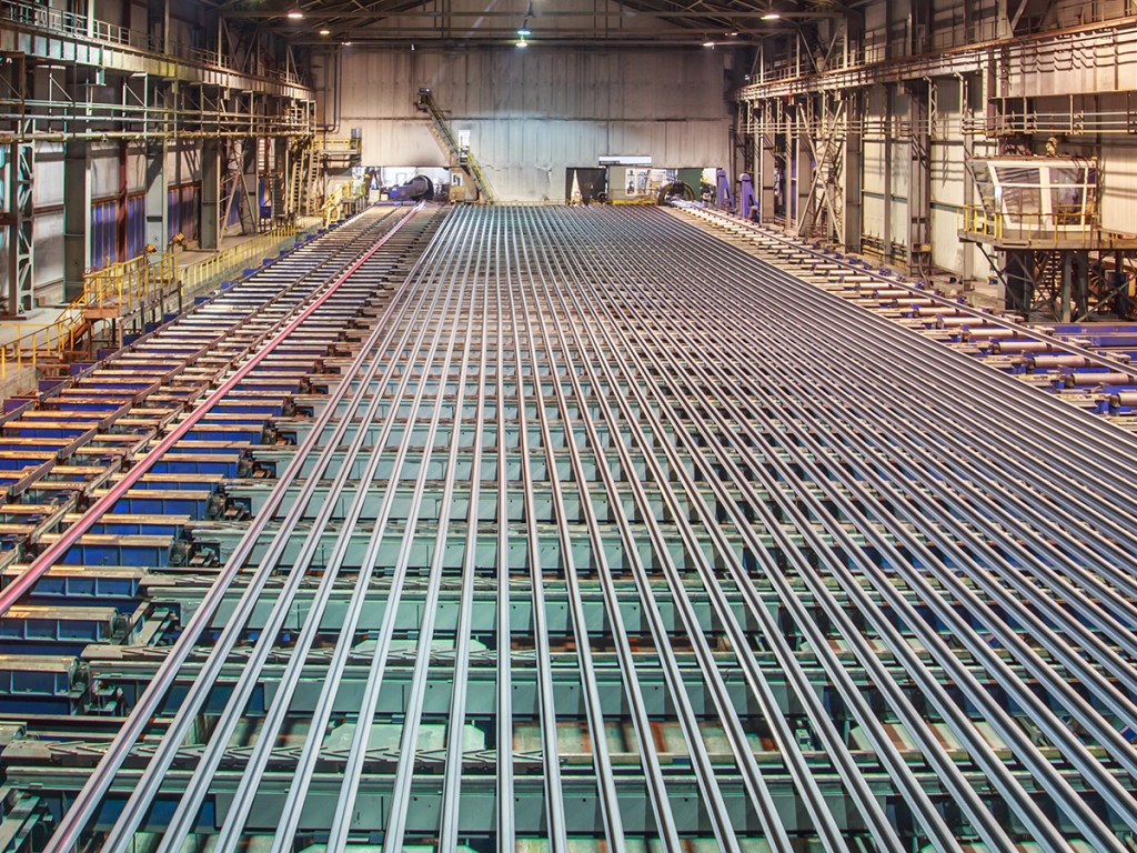 Rolling mill workshop at iron foundry. Stack of steel ingots for railway track.