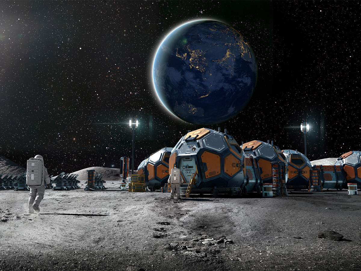 Rear view of an astronaut near some foreground rocks walking towards a lunar base camp made from group of linked habitation pods, solar panels and equipment.