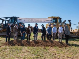 Image showing several officials shoveling ground in front of two construction vehicles carrying a banner
