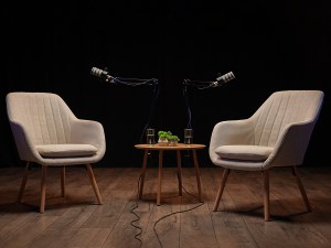 Cozy podcast setting with chairs and microphones, black background