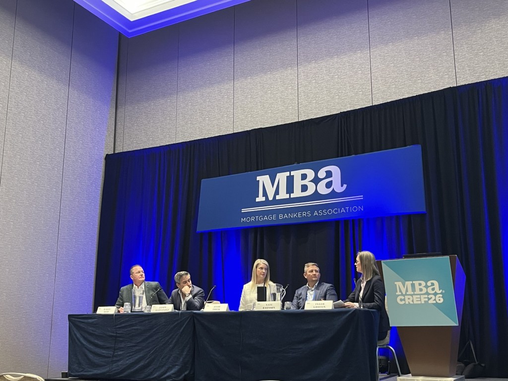 A photo of JLL Capital Markets' Wally Reid, Jason Hernandez of Nuveen, JPMorgan's Julie Thick, Northmarq's Nate Barnson and Tyler Griffin of Lument discussing the on-the ground reality of CRE dealmaking.