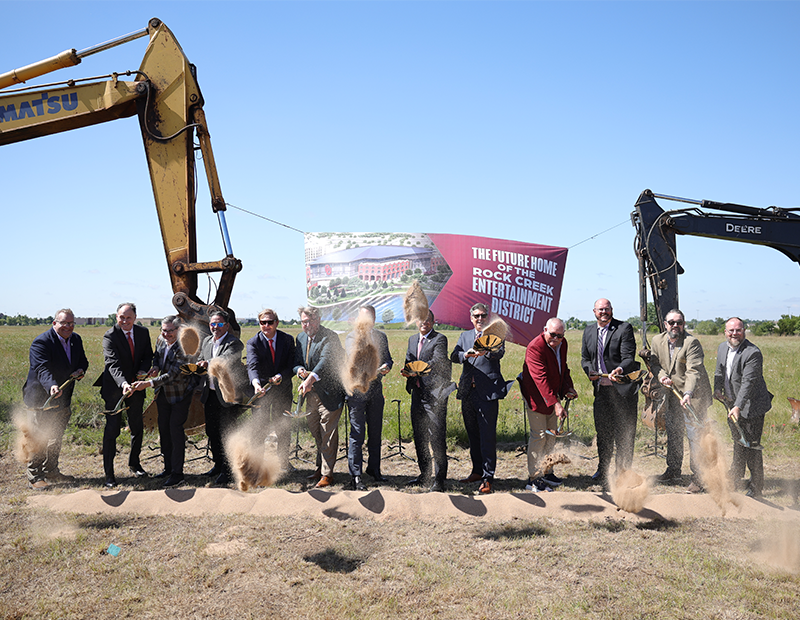 Officials shoveling dirt at the ground breaking of a new mixed-use district in Oklahoma.