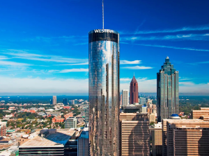 Exterior, aerial shot of the Westin Peachtree Plaza hotel in downtown Atlanta. The building has a cylindrical shape and reflective glass facade
