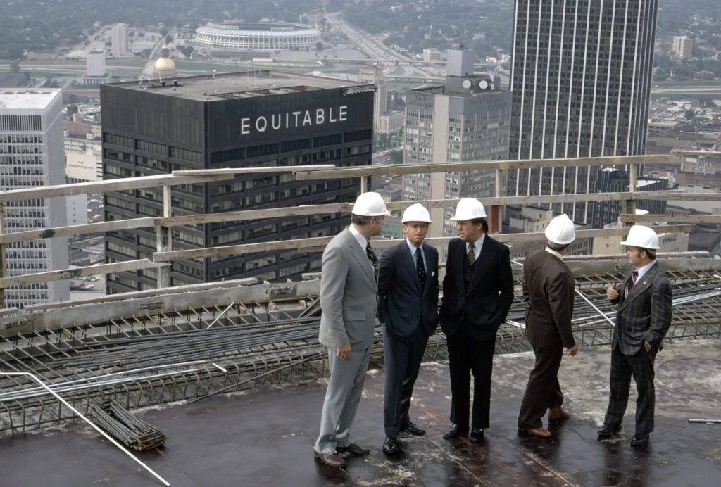 Exterior, aerial view of the rooftop of The Westin Peachtree Plaza with group of five men in suits and hard hats, man in center is John C. Portman, Jr., to his left is Ivan Allen Jr. (former mayor of Atlanta), other men are unidentified