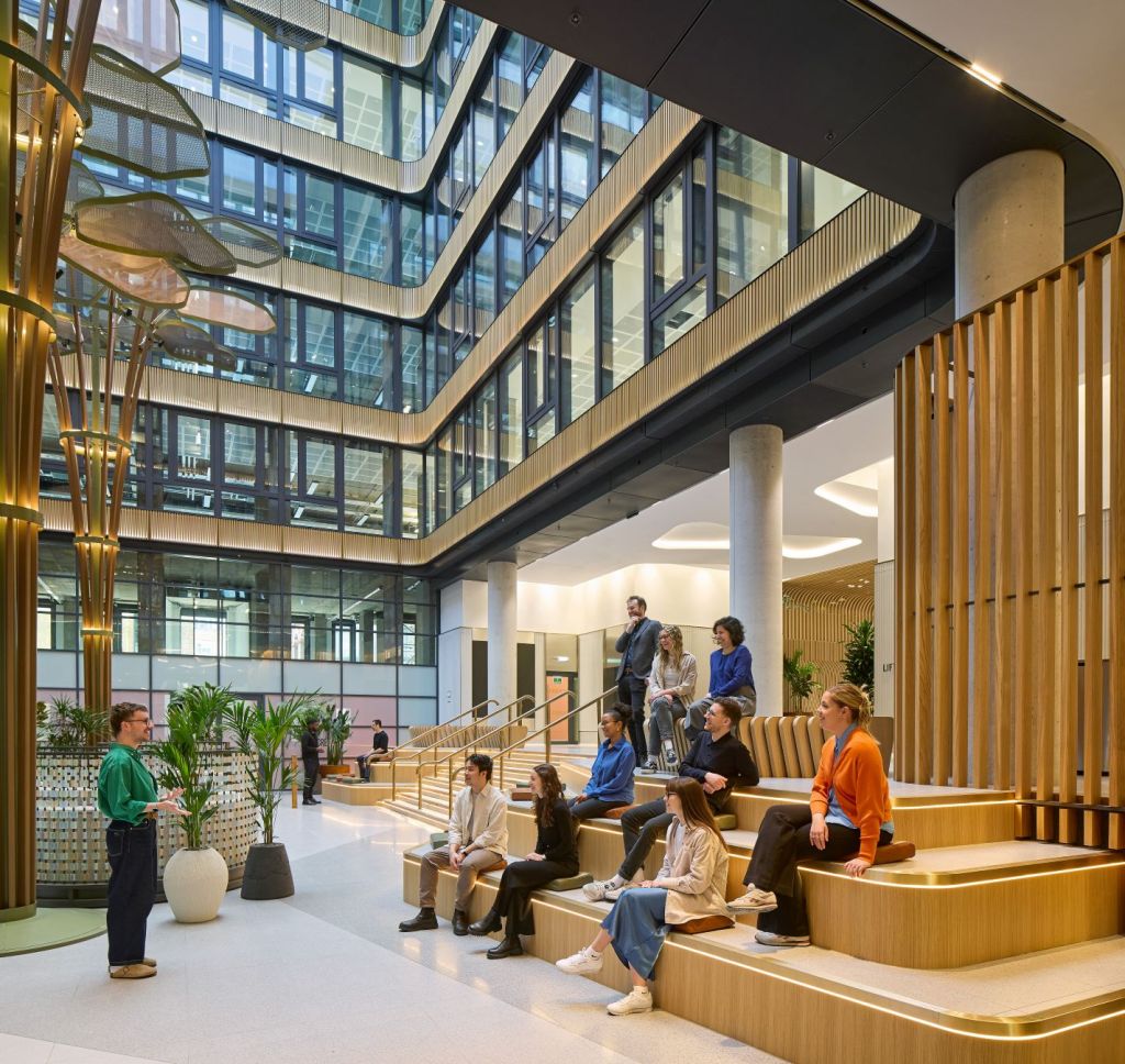 Naturally ventilated atrium at The Acre, with people seated on stepped gathering areas.