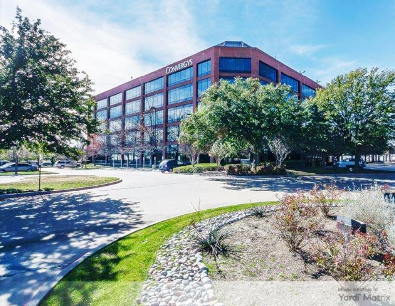 Modern office structure at a street corner, showcasing glass windows and a sleek design in an urban setting.