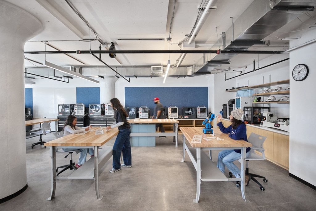 Several individuals seated at tables in an open office environment, working together and sharing ideas.