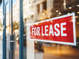 Storefront window displaying a red FOR LEASE sign, indicating available commercial property for business rental