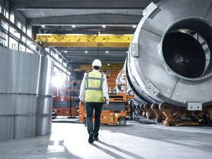 Following Shot of Heavy Industry Engineers Walking Through Manufacturing Factory. In the Background Professionals Working on Construction of Oil, Gas and Fuel Pipeline Transportation Products.